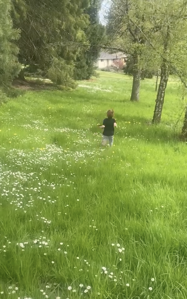 Teacher enjoying the summer by getting outside, image of a child running through field of daises