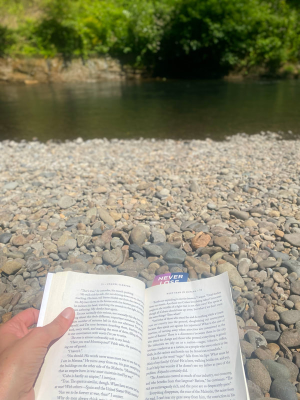 Reading a book at the rocky shore of a river